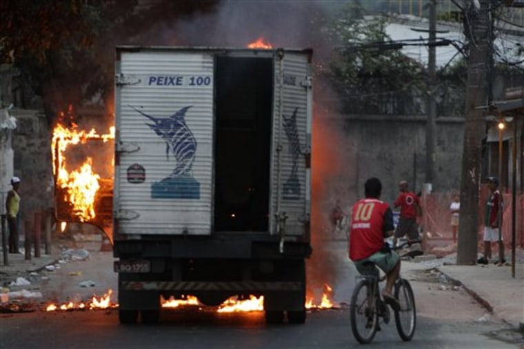People look at a truck allegedly set on fire by drug traffickers at Jacarezinho slum in Rio de Janeiro, Brazil, Wednesday Nov. 24, 2010. Police raided gang-ruled shantytowns and said some 10 suspected criminals died in gunbattles on Wednesday as authorities tried to halt a wave of violence that has rattled rich and poor alike in the Brazilian city. (AP Photo/Felipe Dana)